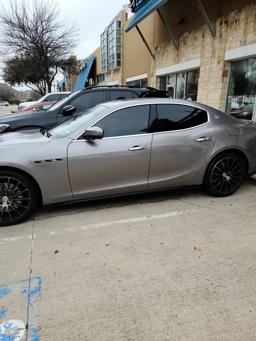 A silver Maserati Ghibli, tinted, outside the Frisco Tint shop